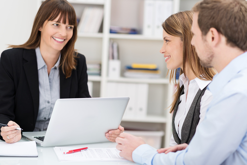 A young couple sitting in an office with a smiling young woman professional