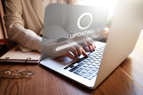 A woman's hand on a laptop which shows updating